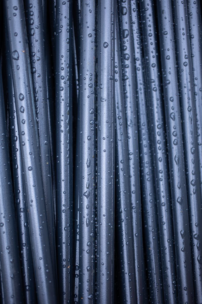services-02 An abstract close-up of vertically arranged wet black pipes with raindrops.
